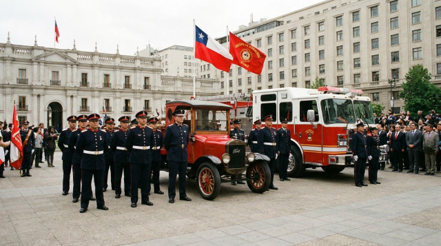 voluntarios del Cuerpo de Bomberos de Chile junto a su carro bomba en una ceremonia del Día Nacional del Bombero el 30 de diciembre