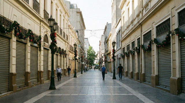 calle comercial de una ciudad chilena con las cortinas de las tiendas cerradas y adornos navideños durante el feriado irrenunciable de Navidad en Chile