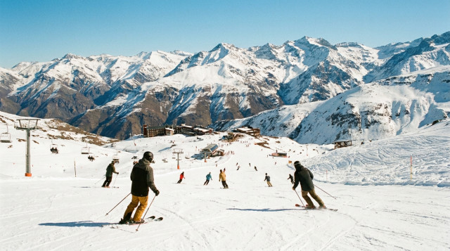 Esquiadores descendiendo por las pistas de Valle Nevado con la inmensidad de la cordillera de fondo